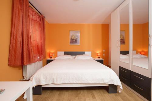 sypialnia z białym łóżkiem i pomarańczowymi ścianami w obiekcie Apartments with a parking space Opatija - 7861 w mieście Opatija