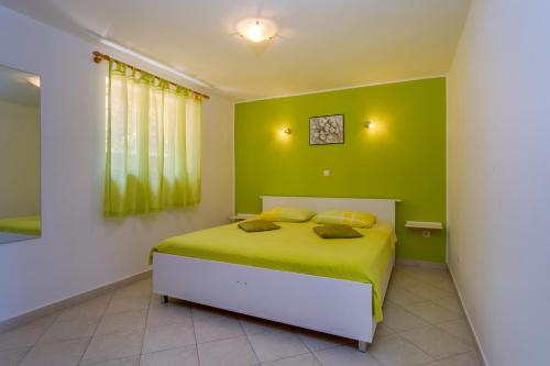 a bedroom with green walls and a bed with two pillows at Apartments with a parking space Mali Losinj (Losinj) - 8067 in Mali Lošinj