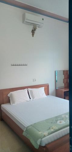 a bedroom with a large white bed with a fan at Green Hills Homestay in Ha Lãm