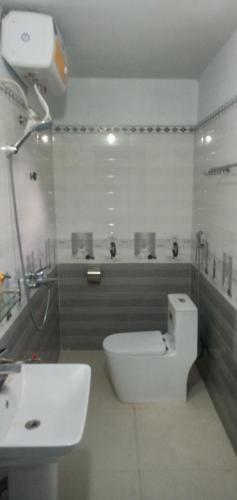 a white bathroom with a toilet and a sink at Green Hills Homestay in Ha Lãm