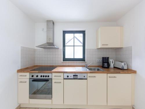 a kitchen with white cabinets and a sink and a window at Comfortable apartment in Eisfeld with bicycle storage in Eisfeld