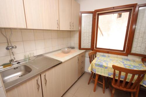a kitchen with a sink and a table and a window at Apartments by the sea Cres - 7875 in Cres