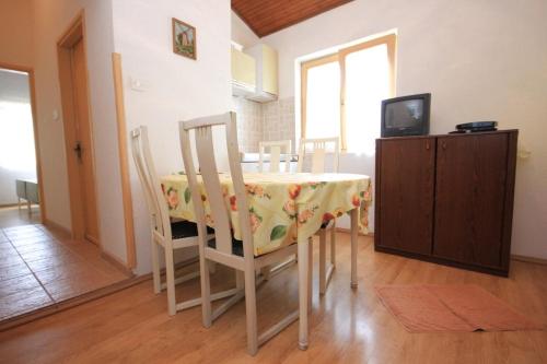 a dining room with a table and chairs and a television at Apartments with a parking space Artatore, Losinj - 7938 in Cunski