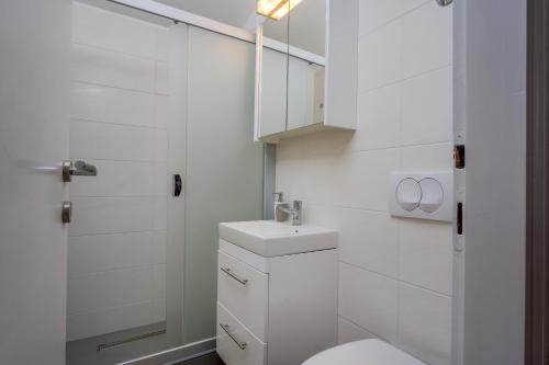 a white bathroom with a toilet and a sink at Apartments by the sea Artatore, Losinj - 7934 in Čunski