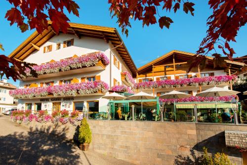 a building with flowers and umbrellas in front of it at Hotel Garni Doris in Castelrotto