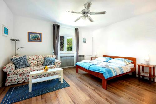 een slaapkamer met een bed en een bank bij Apartments by the sea Artatore, Losinj - 8020 in Čunski