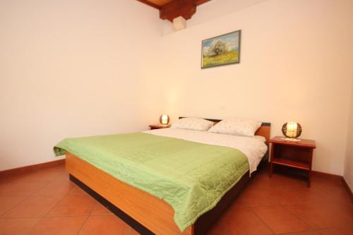 - une chambre avec un lit et une couverture verte dans l'établissement Apartments with a parking space Veli Losinj, Losinj - 8029, à Veli Lošinj