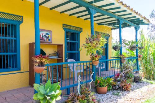 a yellow house with plants on a balcony at FINCA COCUYAL Hospedaje típico paisa in Rionegro