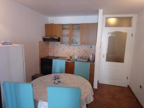 a small kitchen with a table and blue chairs at Apartments with a parking space Icici, Opatija - 7859 in Ičići