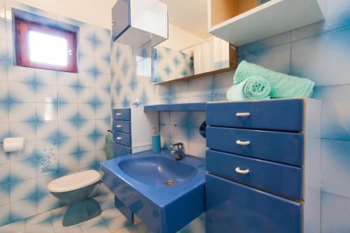 La salle de bains bleue est pourvue de toilettes et d'un lavabo. dans l'établissement Apartments with a parking space Brna, Korcula - 9188, à Smokvica