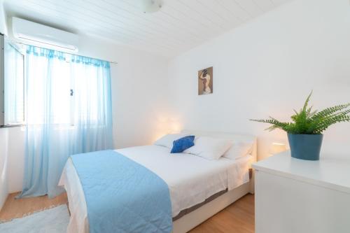 a white bedroom with a bed and a potted plant at Seaside house for families with children Cove Stratincica, Korcula - 9265 in Vela Luka