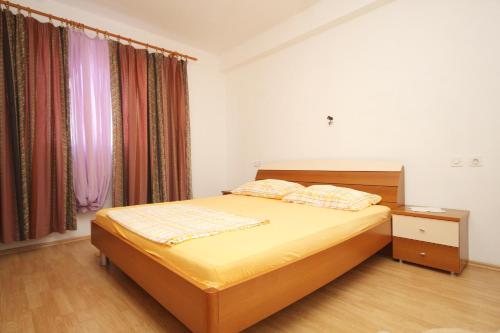 a bedroom with a bed with yellow sheets and curtains at Apartments by the sea Kneza, Korcula - 9164 in Pupnat