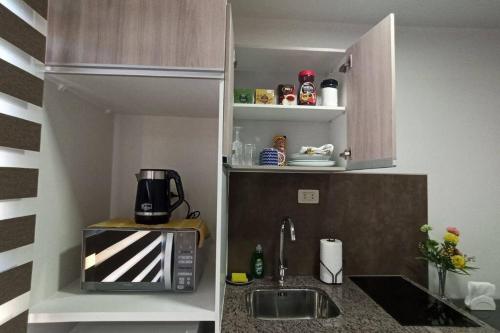 uma pequena cozinha com um micro-ondas e um lavatório em Monoambiente de Lujo en EL PRADO de Cochabamba II em Cochabamba