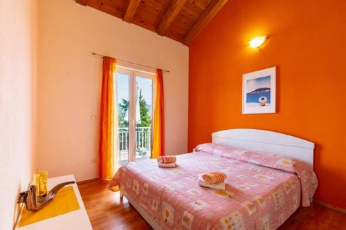 a bedroom with a bed with orange walls and a window at Apartments by the sea Kneza, Korcula - 9168 in Račišće