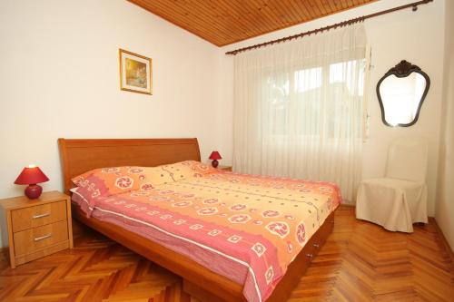 a bedroom with a bed and a window with a chair at Apartments by the sea Brna, Korcula - 9296 in Smokvica