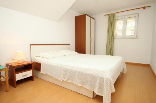 a bedroom with a white bed and a window at Apartments by the sea Kneza, Korcula - 9171 in Pupnat