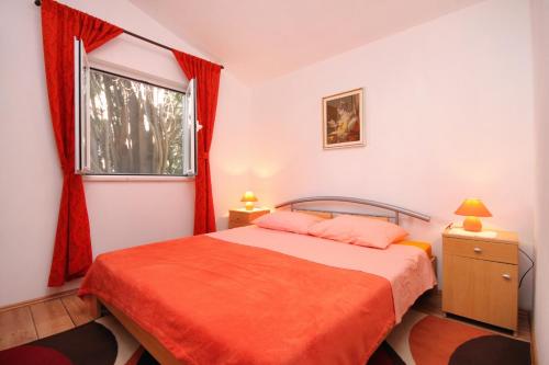 a bedroom with a bed with red curtains and a window at Apartments by the sea Brna, Korcula - 9231 in Smokvica