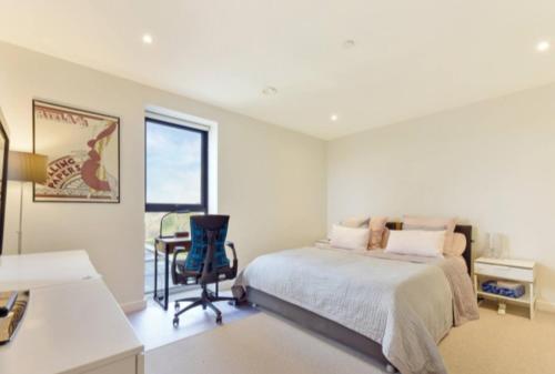 1 dormitorio con cama, escritorio y silla en Lovely Luminous 3 Bed Flat, with secure Ev Parkng, en Londres