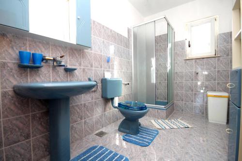 y baño con aseo azul y lavamanos. en Seaside apartments with a swimming pool Kneza, Korcula - 9269, en Račišće
