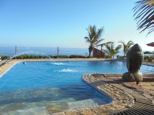 a swimming pool with a statue next to the ocean at Balihai Bungalows in Canoas De Punta Sal