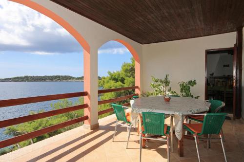 a table and chairs on a porch with a view of the water at Seaside secluded apartments Grscica, Korcula - 9228 in Prizba