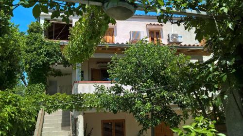 a white building with trees in front of it at Apartment Nerezine 8049b in Nerezine