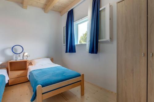 a bedroom with a bed and a window with blue curtains at Apartment Nerezine 8049b in Nerezine