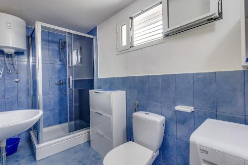 a blue tiled bathroom with a toilet and a sink at Apartment Nerezine 8049b in Nerezine