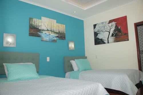 two beds in a room with blue lighting at Hotel Dubai in Manizales