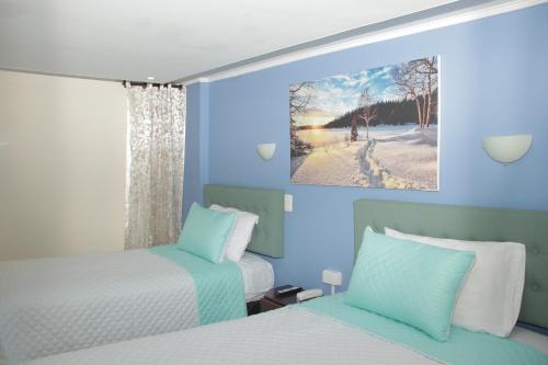 Habitación azul con 2 camas y ventana en Hotel Dubai en Manizales