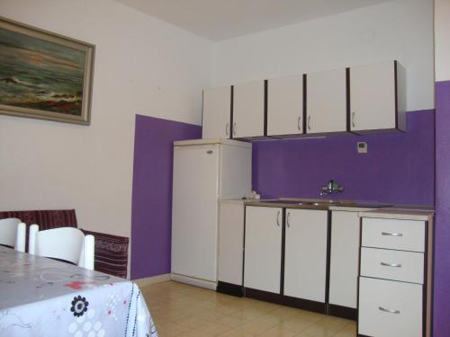 uma cozinha com armários brancos e uma parede roxa em Apartments and rooms by the sea Sumartin, Brac - 2953 em Sumartin
