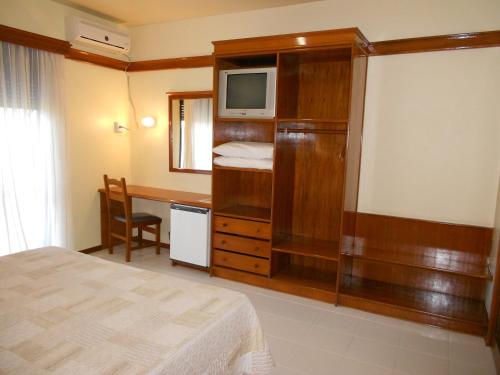 a bedroom with a bed and a desk with a television at River Hotel in Uruguaiana