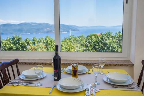a table with a wine bottle and plates and glasses at Holiday house with a swimming pool Zagore, Opatija - 7922 in Zagorje