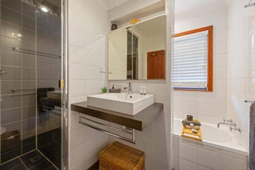 a white bathroom with a sink and a mirror at Little Beach Bungalow - at Bartlett's in Bonny Hills