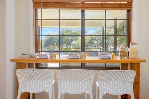 a dining room table with four chairs and a large window at Little Beach Bungalow - at Bartlett's in Bonny Hills