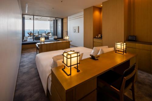 a bedroom with a bed and a desk with two lights at Pearl Star Hotel ATAMI in Atami