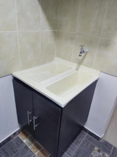 baño con lavabo blanco y armario negro en Armenia Apartamento, en Armenia