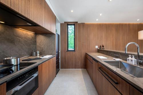 a kitchen with wooden cabinets and a sink at Ryoun by H2 Life in Kutchan