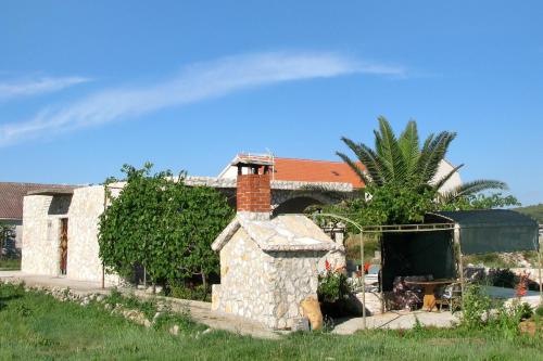 a house with a stone fireplace in a yard at Apartments by the sea Krapanj, Sibenik - 9258 in Brodarica