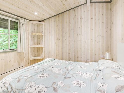 a bedroom with a bed in a room with wooden walls at Lakeside Cabin in Dunkeswell