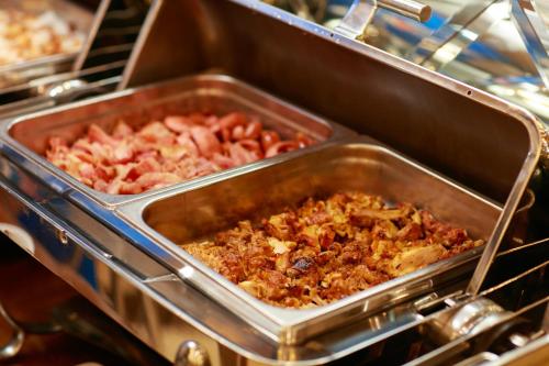 Una sartén de metal llena de comida en un buffet. en Babylon Grand Hotel & Spa, en Hanói