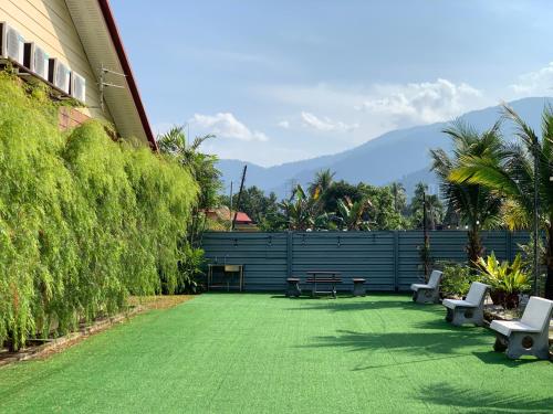 a yard with benches and a fence with mountains in the background at Raintown Cottage in Taiping
