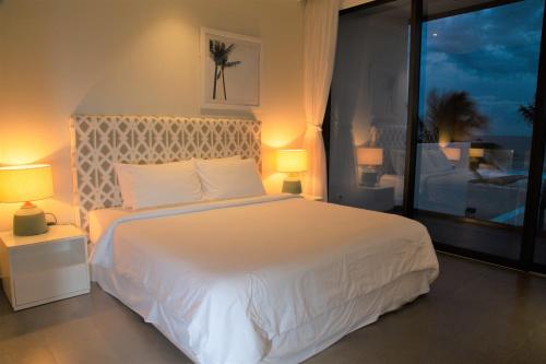 a bedroom with a large white bed with two lamps at Faru Beachfront Villa Sanctuary Ho Tram in Ho Tram