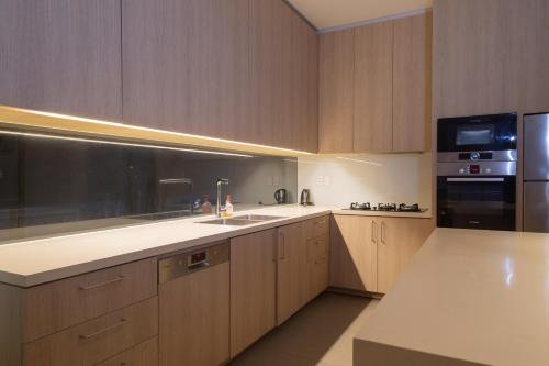 a kitchen with wooden cabinets and a white counter top at Faru Beachfront Villa Sanctuary Ho Tram in Ho Tram