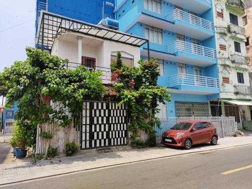 ein rotes Auto, das vor einem blauen Gebäude parkt in der Unterkunft Hà Tiên Homestay in Hà Tiên