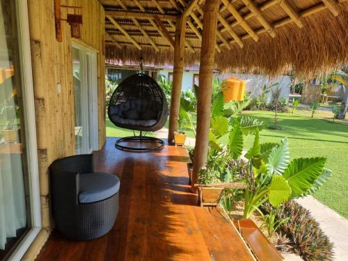 a porch of a house with a chair and a thatch roof at Sumba Retreat Kerewe in Waikabubak