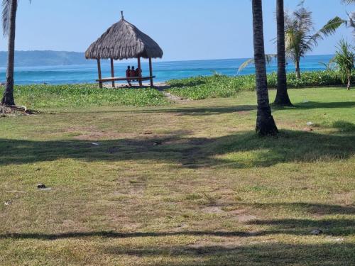 a group of people sitting in a gazebo on the beach at Sumba Retreat Kerewe in Waikabubak