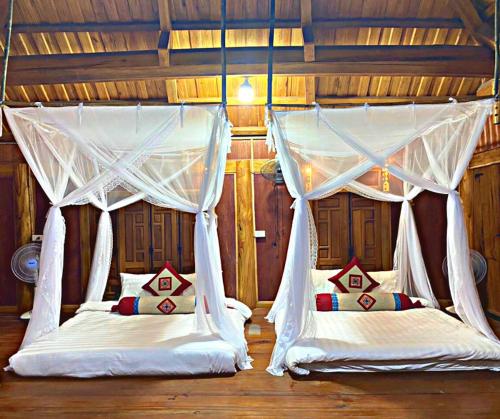 Làng BangにあるPu Luong May Home & Cafeの白いカーテン付きのベッド2台が備わる客室です。