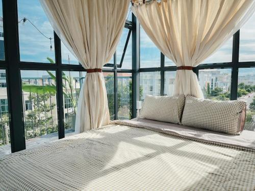 un grande letto in una stanza con ampie finestre di LIM House a Phan Thiet