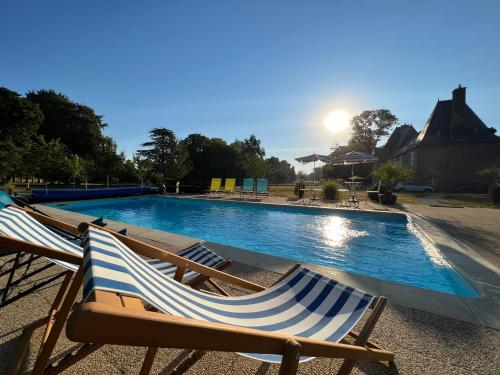 2 sillas de jardín sentadas junto a una piscina en Le gîte du Château de la Croix Chemin, en Saint-Léger-des-Prés